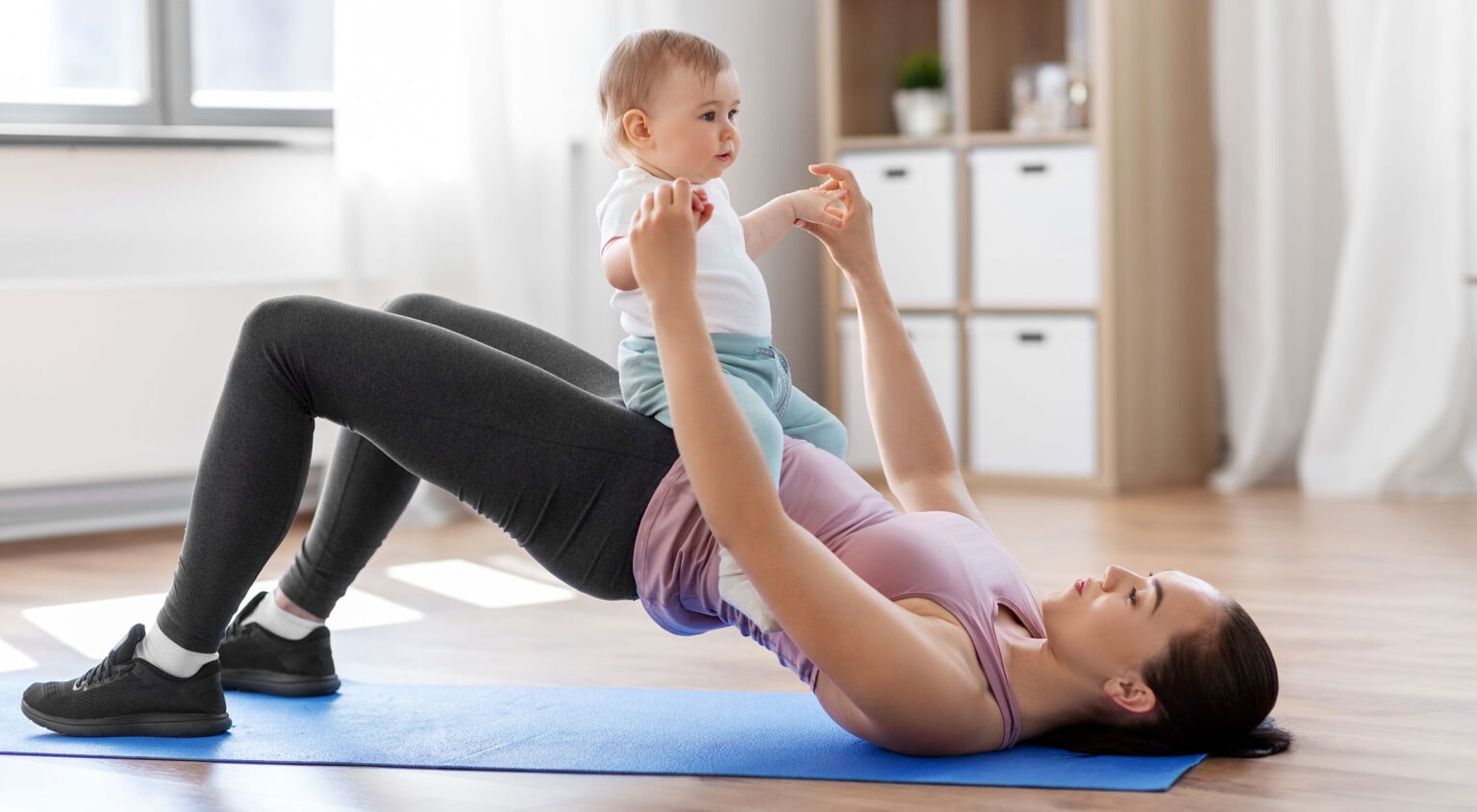 family, sport and motherhood concept - mother with little baby exercising at home